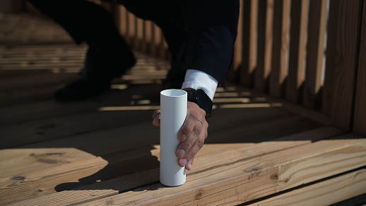 Handheld laser sensor held against a wooden deck